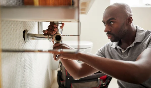 a male plumber fixing a bathroom faucet in Grand Prairie, TX a male plumber fixing a bathroom faucet in Grand Prairie, TX